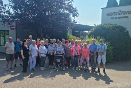 Die Reisegruppe hat sich auf einem Platz vor einem großen Baum und dem Eingang zum Ressort aufgestellt.