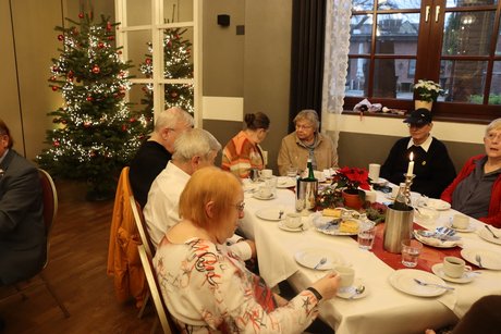 Mehrere Menschen sitzen an festlich gedeckten Tischen.