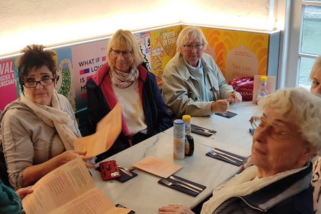 die Mitgleider sitzen zusammen an Tischen und warten auf`s Essen