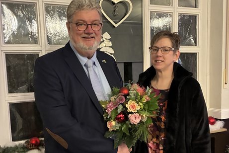 Ein Mann h&auml;lt einen Blumenstrau&szlig; und gratuliert einer Frau