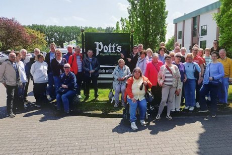 Einige Menschen posieren als Gruppe vor einem Firmenschild