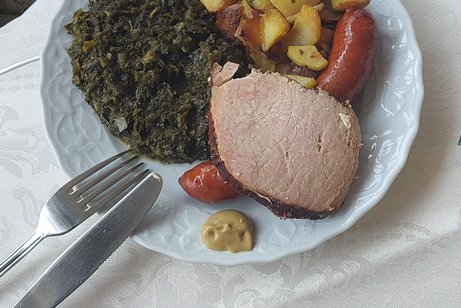 Zu sehen ist eine Portion Gr&uuml;nkohl mit Bratkartoffeln, Mettenden und Kassler.