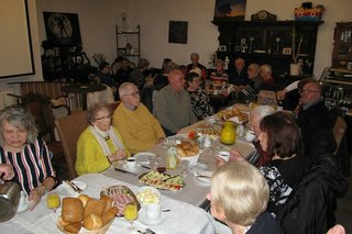 Viele Menschen sitzen gemeinsam beim Frühstück an einem langen Tisch.