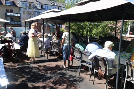 Menschen sitzen an langen Tischen im Au&szlig;enbereich.