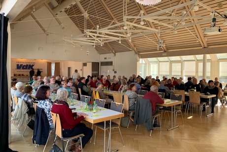 Saal mit Menschen an Tischen sitzend