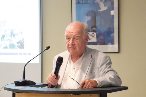 Ein Mann spricht in ein Mikrophone an einem Rednerpult.