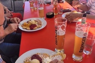 Eine Gruppe Menschen sitzt gemeinsam an einem Tisch bei kalten Getränken und Waffeln.