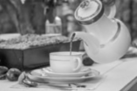 Kaffee wird aus einer Kaffeekanne in eine Kaffeetasse eingeschenkt