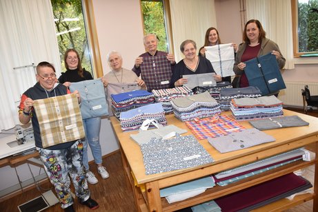 Taschen aus Hemden. Nachhaltige Geschenke f&uuml;r G&auml;ste des VdK zeigen (v.l.) Nadine Klak, Jana Sahle, Marita Maschke, Adolf und Eveline Gerdes, Christina G&auml;rtner und Daria Elpers in der N&auml;hwerkstatt von Camphill Sellen.