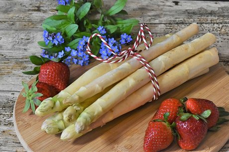 Spargel mit Erdbeeren auf einem Holzbrett