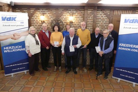 Ehrung der Jubilare 9 Personen stehen zwischen den Bannern des VdK