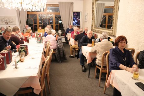 Mehrere Menschen sitzen an gedeckten Tischen.