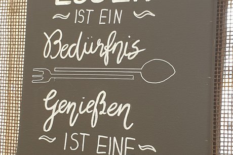 Tafel mit dem Spruch: Essen ist ein Bedürfnis. Genießen ist eine Kunst.