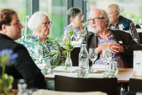Menschen sitzen an festlich gedeckten Tischen.