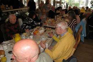 Viele Menschen sitzen gemeinsam beim Frühstück an einem langen Tisch.