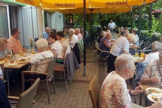 Viele Menschen sitzen auf der Außenterrasse eines Restaurants beim Essen