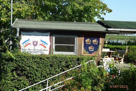 Werbeschild an einem kleinen Holzschuppen: Grachten-Treene-Fahrten, im Hintergrund die Gracht.