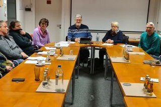 Menschen sitzen gemeinsam an einem Konferenztisch