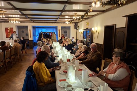Jutta Baumhold stehend lie&szlig;t eine Weihnachtsgeschichte. Mitglieder sitzen an den Tischen und h&ouml;ren gespannt zu.