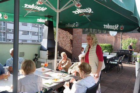Grillnachmittag vom VdK Ortsverband Altendorf gemeinsam mit dem Ortsverband Borbeck. Eine Frau steht an einem Tisch und spricht mit den Teilnehmern.