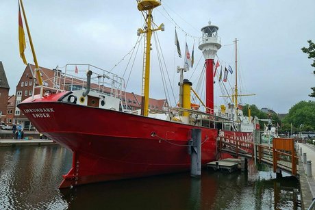 Ein großes, rotes Schiff mit der Aufschrift Amrumbank Emden am Heck liegt vertäut am Kai.