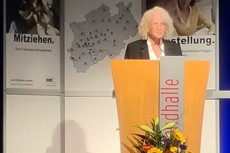 Eine Frau steht an einem Rednerpult auf der Bühne.