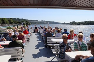 Mitglieder aus mehreren Ortsverbänden sitzen an Tischen, im Außenbereich auf dem Oberdeck des Schiffes zusammen.