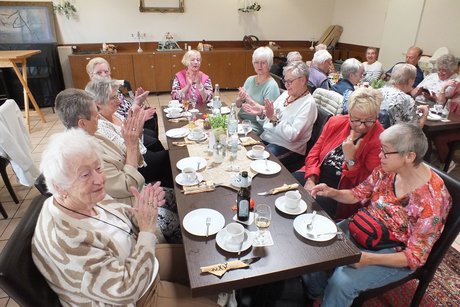 Mehrere Menschen sitzen an langen Tischen.