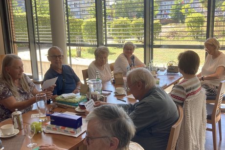 Menschen sitzen an einem Langen Tisch und spielen Bingo.