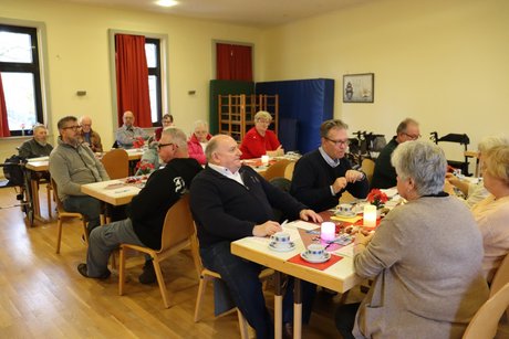 Mitglieder sitzen an gedeckten Tischen.