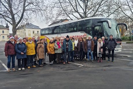 Das Bild zeigt die Teilnehmer am Tagesausflug nach Rüdesheim als Gruppe aufgestellt vor dem Reisebus auf einem baumbestandenen Parkplatz.