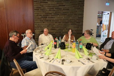 Mehrere Personen sitzen an einem runden Tisch und unterhalten sich.