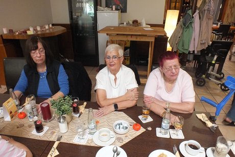 Drei Frauen sitzen am Tisch und lauschen der Vorstellung des Musikers.