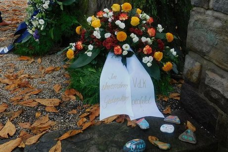 Großer Kranz aus Immergrün und gelben, weißen und orangen Herbstblumen mit einer weißen Schleife des VdK Coesfeld