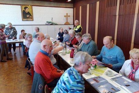 Mehrere Personen sitzen an langen Tischen.