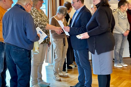 Personen stehend bei Gratulation zur Ehrung vor VdK Fahne
