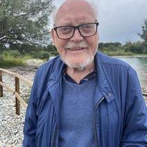 Das Bild zeigt Karl-Heinz in blauem Poloshirtund blauer Sommerjacke an einem Strand