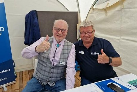 Zwei Männer sitzen gemeinsam am Messestand