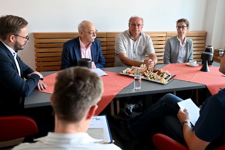 Drei Männer und eine Frau sitzen an einem Tisch