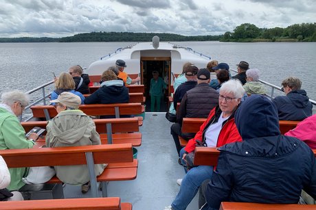 Schifffahrt auf dem Kellersee Menschen auf Bänken auf einem Schiff auf dem See