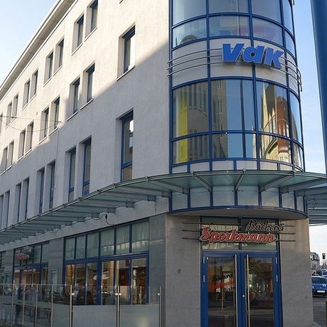 Fassade eines Eckgebäudes mit großer Glasfassade, darüber das blaue Logo des VdK.