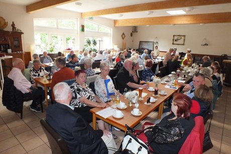 Viele Mitglieder sitzen an langen Tischen.