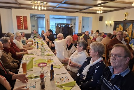 Alle Anwesenden sitzen an den Tischen und verfolgen gespannt die Ziehung der Kugeln.