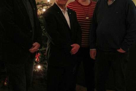 Vier Menschen stehen zum Gruppenfoto aufgestellt vor einem Weihnachtsbaum.