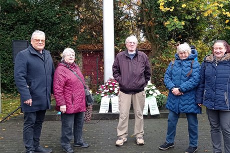 Kranzniederlegung zum Volkstrauertag in Essen-Dellwig. 5 Personen stehen für ein Foto zusammen vor den niedergelegten Kränzen.