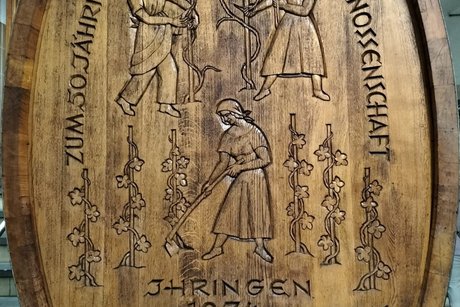 Zu sehen ist ein sehr schön mit Schnitzarbeit verziertes hölzernes Weinfass im Keller der Ihringer Winzergenossenschaft.