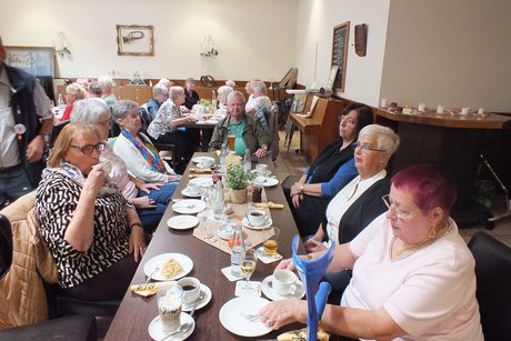 Mehrere Menschen sitzen an langen Tischen.