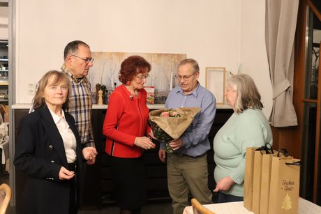 F&uuml;nf Personen stehen zusammen und ein Mann gibt einer Frau einen Blumenstaru&szlig;.