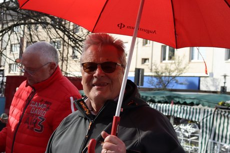 Zwei M&auml;nner stehen an einem Stehtisch. der Vordere hat einen roten Schirm in der Hand.