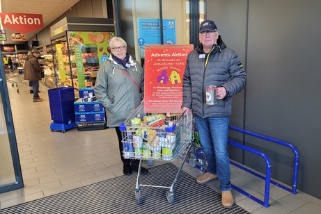 Hier stehen 2 Mitglieder mit dem schon gefüllten Einkaufswagen beim Aldi und nehmen Spenden an.
